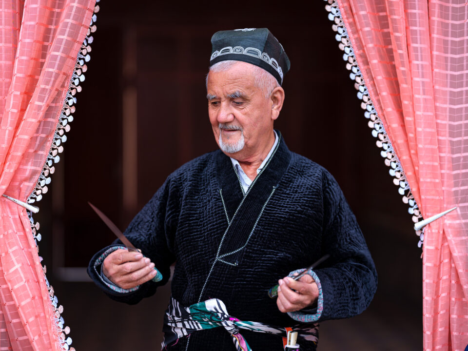 一位来自乌兹别克斯坦安集延的铁匠大师，手持一把自己制作的刀