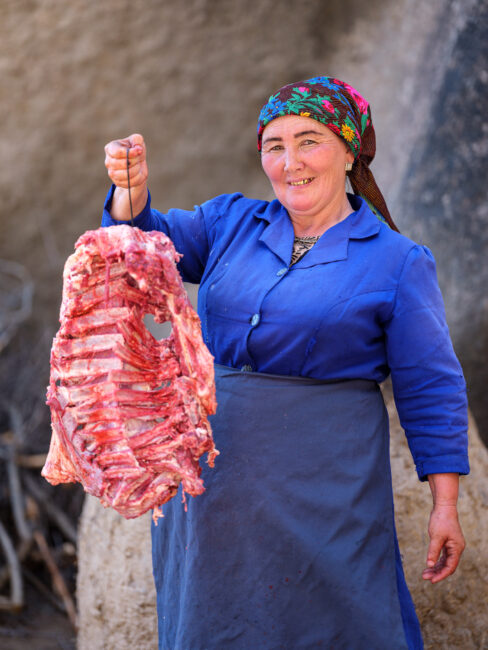 乌兹别克斯坦，一名妇女拿着挂在烤串上的羔羊
