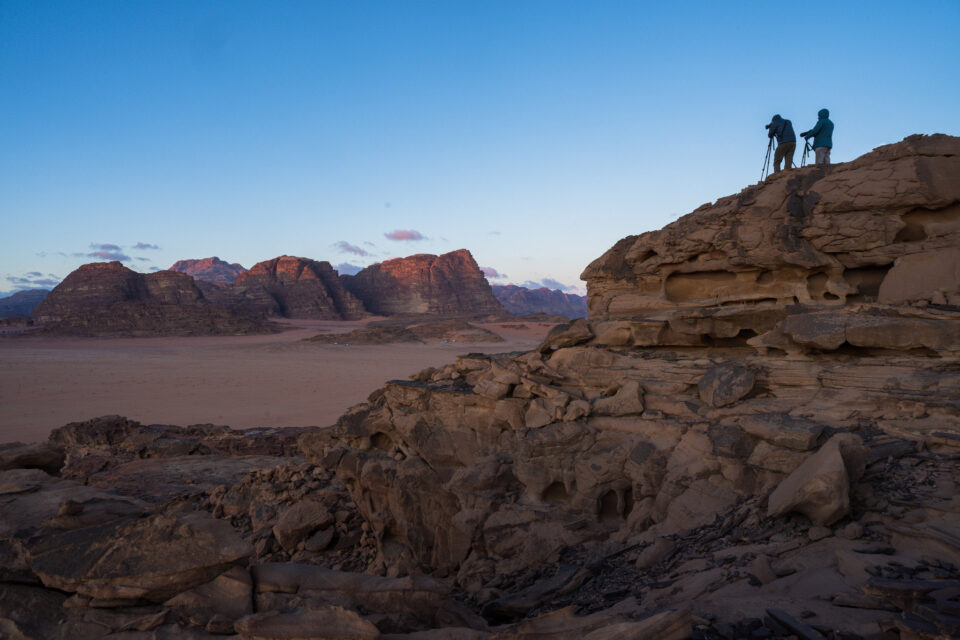 两个风景摄影师带着三脚架从高处俯瞰日出